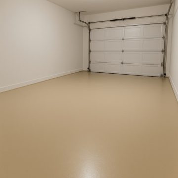 Pusty, odnowiony garaż z równą posadzką żywiczną w klasycznym kolorze beżowym RAL 1001.
