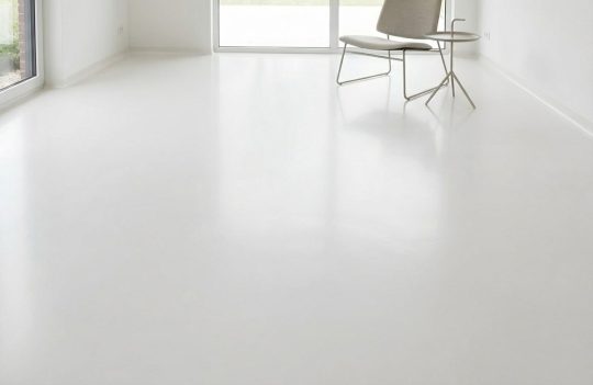 Przestronne, jasne pomieszczenie z gładką, lśniącą podłogą w kolorze RAL 7035, odbijającą światło z dużych okien.