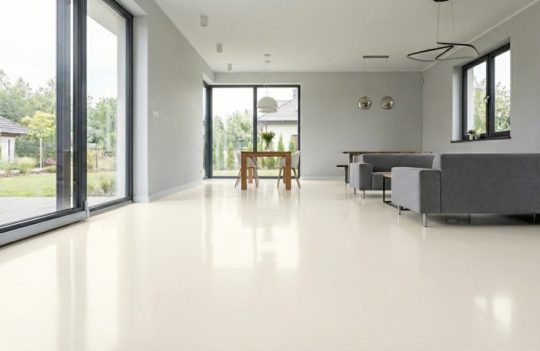 Błyszcząca podłoga w kolorze RAL 9003 dominuje w jasnym, nowoczesnym wnętrzu otwartego planu.